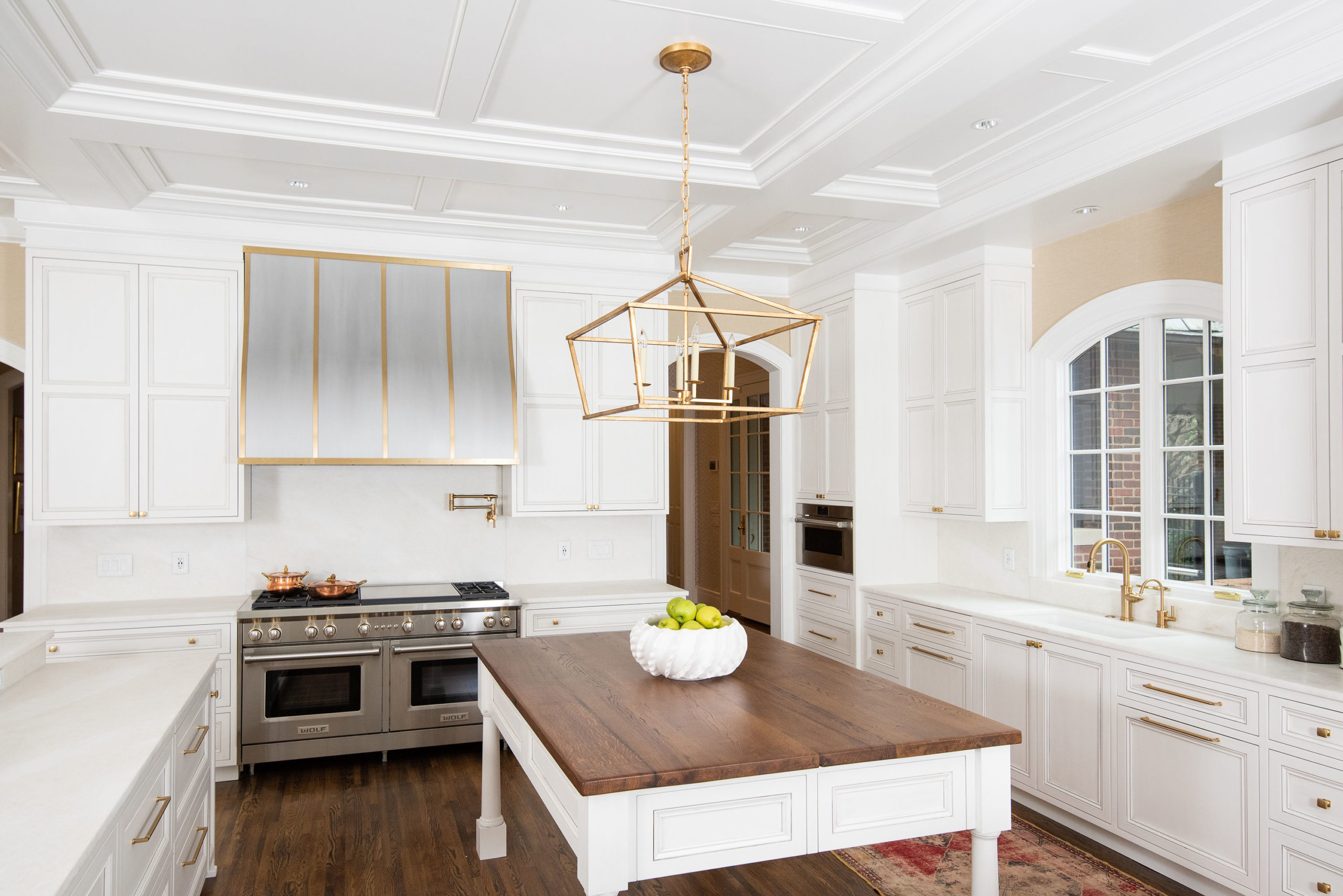 large white kitchen with dark hardwood floors and white cabinets with gold accents