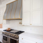 white cabinets and stainless steel oven with stove top and gold accents in kitchen